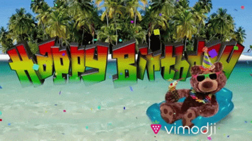 A Teddy Bear Sitting On A Beach With The Words Happy Birthday Behind Him GIF