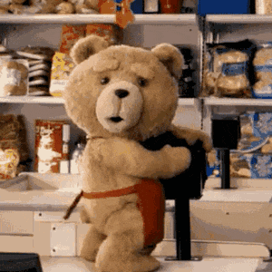 A Teddy Bear Wearing A Red Apron Is Standing In Front Of A Cash Register . GIF