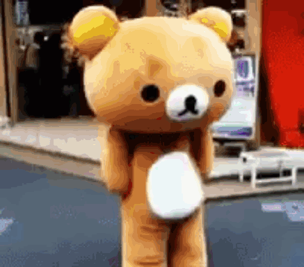 A Teddy Bear With A Yellow Ear Is Standing On A Street GIF