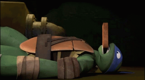 A Teenage Mutant Ninja Turtle Is Laying On The Floor GIF