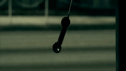 A Telephone Is Hanging From A Pole In The Dark . GIF