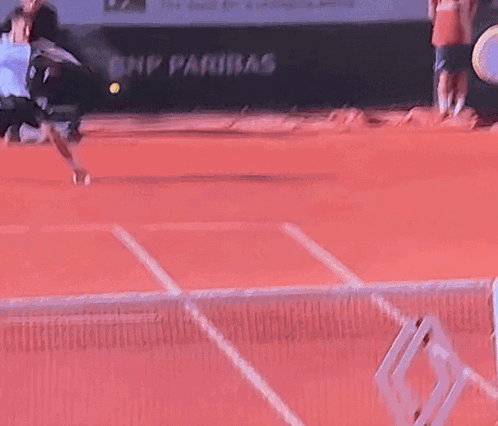 A Tennis Ball Is Being Thrown In The Air On A Red Court GIF