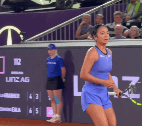 A Tennis Player In A Blue Outfit Is Holding A Tennis Racquet In Front Of A Sign That Says Litz Ag GIF