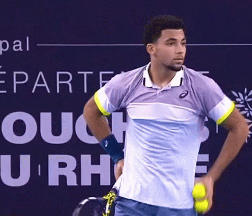 A Tennis Player Is Holding A Tennis Ball In Front Of A Sign That Says U Rh GIF