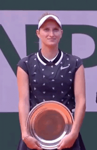 A Tennis Player Is Holding A Trophy And Smiling . GIF