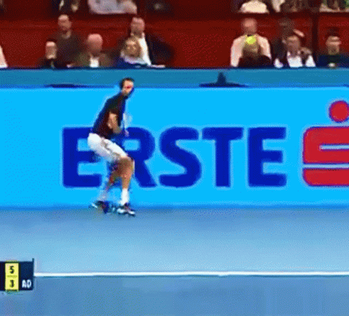 A Tennis Player Is Jumping In Front Of A Large Blue Sign That Says Erste GIF