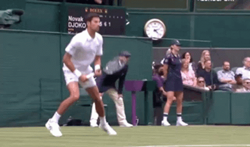 A Tennis Player Is Jumping In The Air On A Tennis Court GIF