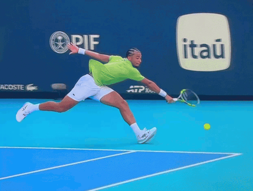 A Tennis Player Is Jumping In The Air While Holding A Racket In Front Of An Advertisement For Itaú GIF