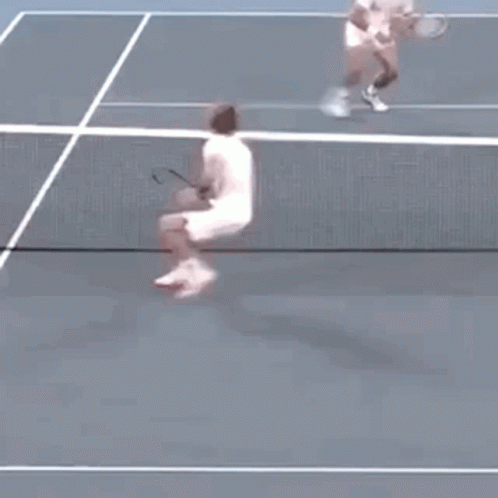 A Tennis Player Is Jumping In The Air While Holding A Tennis Racquet . GIF