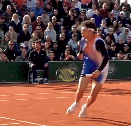 A Tennis Player Is Running On A Court With A Crowd Behind Him GIF