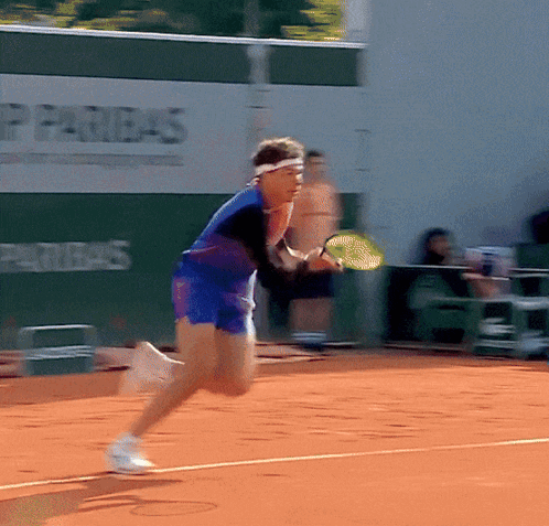 A Tennis Player Is Running On A Court With An Advertisement For Paribas Behind Him GIF