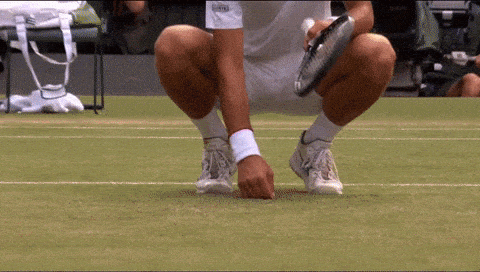 A Tennis Player Is Squatting Down On The Court With A Racket In His Hand GIF