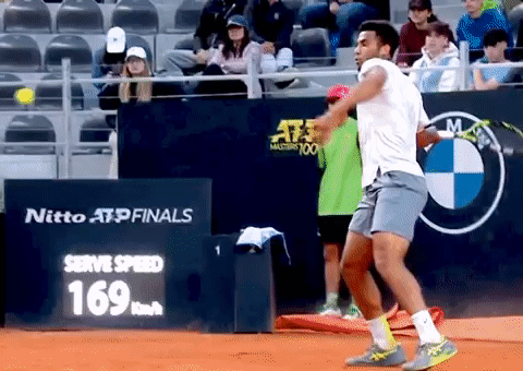 A Tennis Player Is Swinging A Racket In Front Of A Sign That Says Nitto Atp Finals GIF