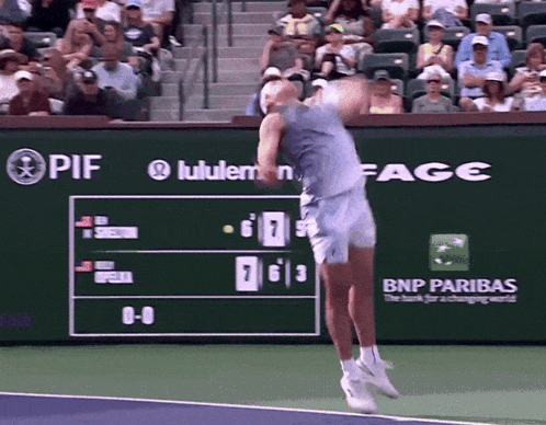A Tennis Player Is Swinging A Tennis Racket In Front Of A Scoreboard That Says Bnp Paribas GIF