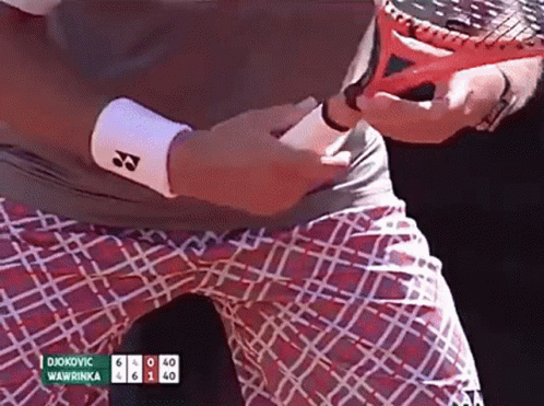 A Tennis Player Named Djokovic Is Holding A Tennis Racquet In His Hand GIF
