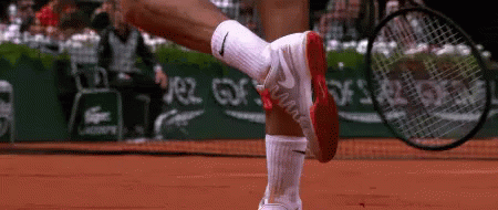 A Tennis Player Wearing Nike Socks Is Holding A Tennis Racquet On A Court GIF