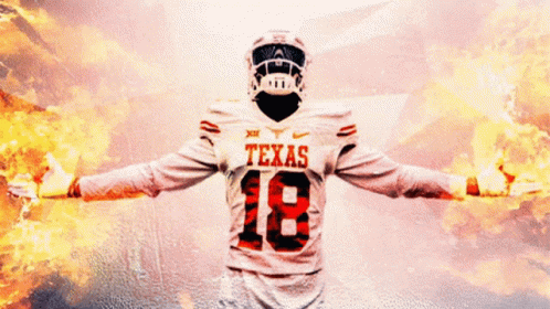 A Texas Football Player With His Arms Outstretched In Front Of A Fire Background GIF