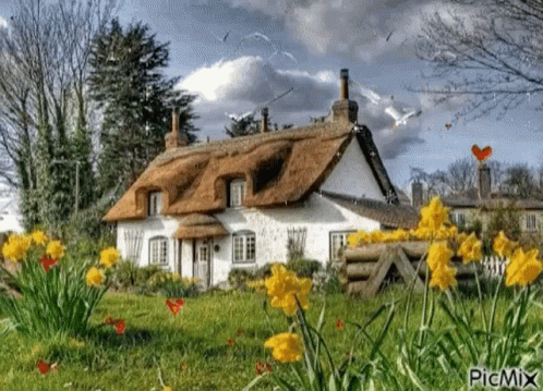 A Thatched Roofed Cottage With Flowers In Front Of It GIF