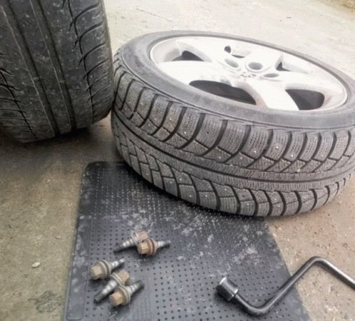 A Tire Is Sitting On A Black Mat Next To A Wheel Wrench GIF