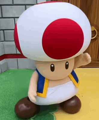 A Toad From Super Mario Bros Is Standing On A Green Surface . GIF