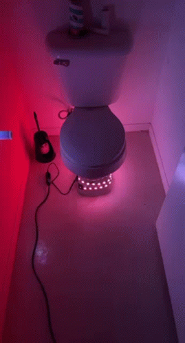 a toilet sits in a bathroom next to a toothbrush and paper towels
