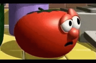 A Tomato From The Veggie Tales Cartoon Is Sitting On A Table . GIF