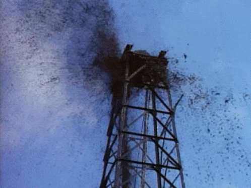 A Tower With A Blue Sky Behind It And A Lot Of Smoke Coming Out Of It GIF