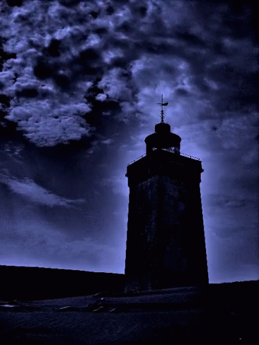 A Tower With A Cross On Top Of It Is Silhouetted Against A Dark Blue Sky GIF