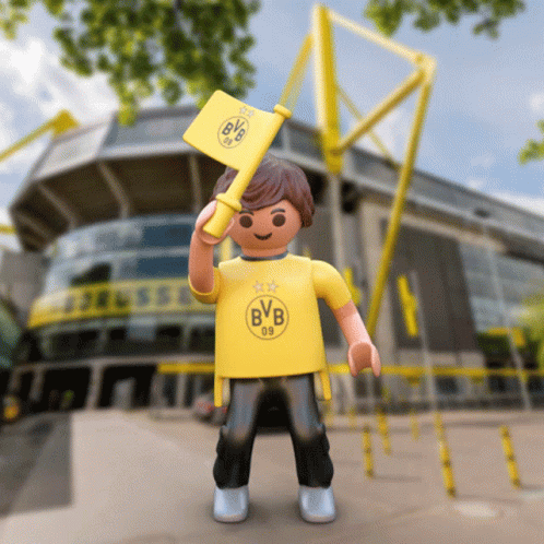 A Toy Boy Wearing A Yellow Bvb Shirt Holds A Yellow Flag GIF