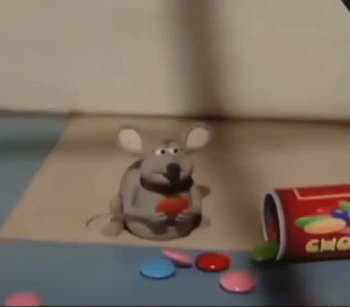 A Toy Mouse Is Sitting On A Table Next To A Bottle Of Candy . GIF