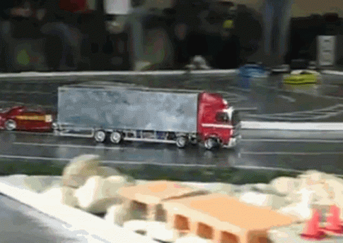 A Toy Truck Is Driving Down A Road Next To A Car GIF