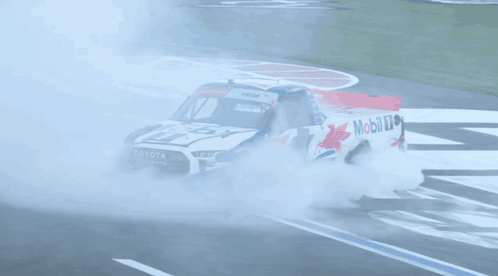 A Toyota Truck Is Driving Down A Race Track With Smoke Coming Out Of It GIF