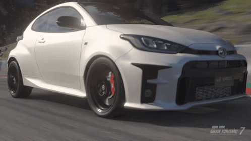 A Toyota Yaris Is Driving Down A Road In A Video Game Called Gran Turismo 7 GIF