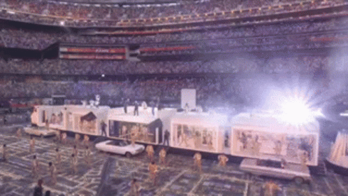 a train is being pulled by cars in a stadium with a crowd in the background