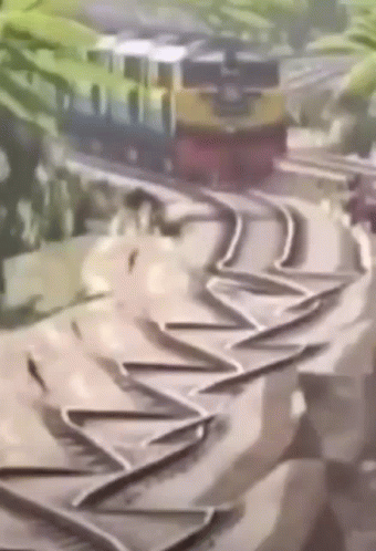 A Train Is Going Down A Curve On A Track . GIF