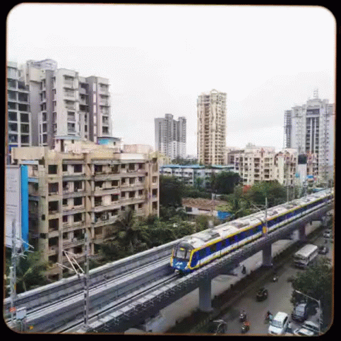 A Train Is Going Down A Track In A City With Buildings In The Background . GIF