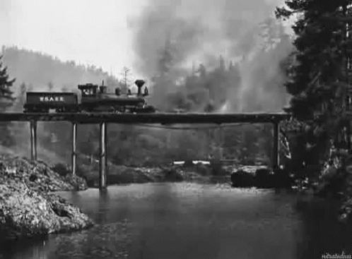 A Train Is Going Over A Bridge Over A River In A Black And White Photo . GIF