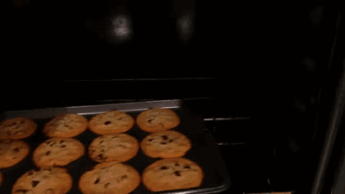A Tray Of Chocolate Chip Cookies Being Taken Out Of An Oven GIF