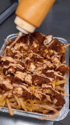 A Tray Of French Fries Is Being Poured With Ketchup GIF