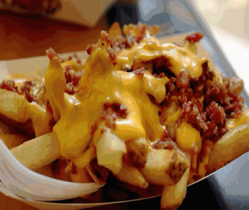 A Tray Of French Fries With Cheese And Bacon On Them GIF