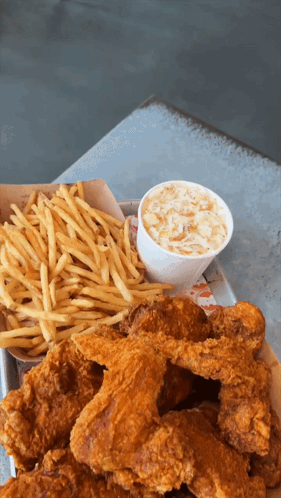 A Tray Of Fried Chicken Wings And French Fries With Coleslaw GIF