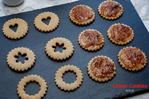 A Tray Of Linzer Cookies Sits On A Black Surface GIF
