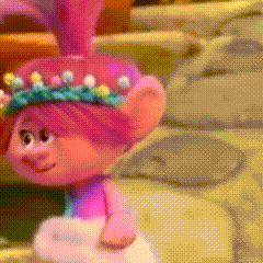 A Troll Doll With Pink Hair And A Crown Of Flowers On Her Head . GIF