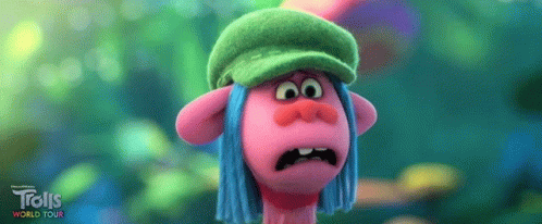 A Troll Wearing A Green Hat And Blue Hair Is Making A Funny Face . GIF
