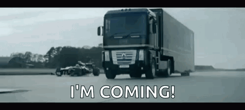 A Truck Is Driving Down A Road Next To A Race Car . GIF