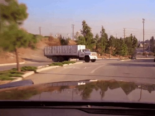 A Truck With A Fence On The Back Is Driving Down The Road GIF