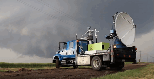 A Truck With A Large Satellite Dish On The Back Is Parked On A Dirt Road GIF