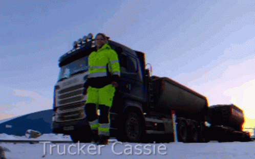 A Trucker Cassie Is Standing In Front Of A Truck In The Snow GIF