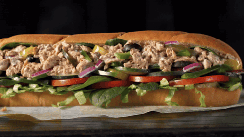 A Tuna Sandwich With Lettuce Tomatoes And Olives On A Bun GIF
