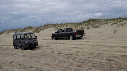 A Van And A Truck Are Parked In The Sand GIF